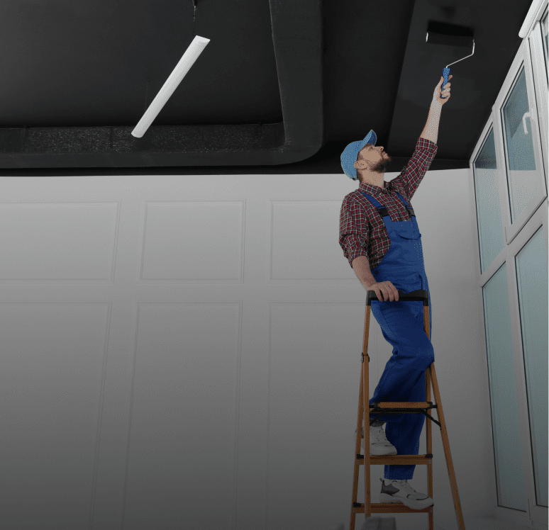 Worker painting ceiling with roller brush